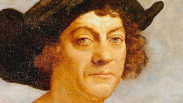 Portrait of a man with curly brown hair, wearing a large black hat