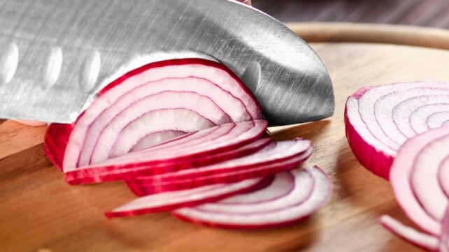 Knife cutting red onions up close