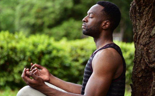 man leaning against a tree meditating
