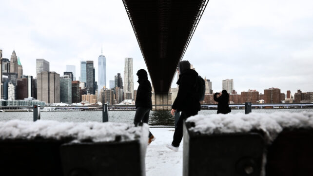 People walking under a bridge in snowy weather