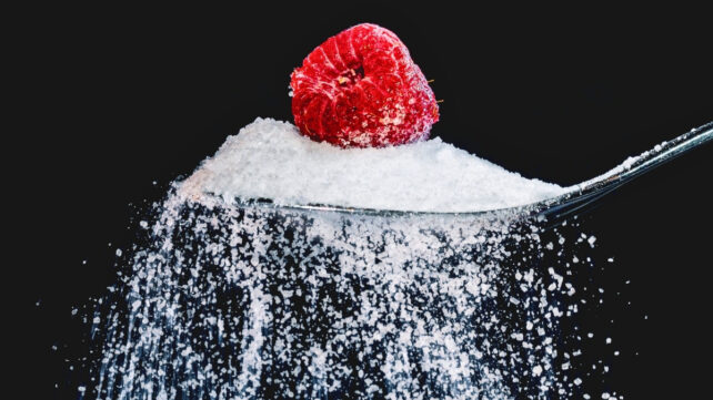 A spoonful of white sugar with a raspberry on top