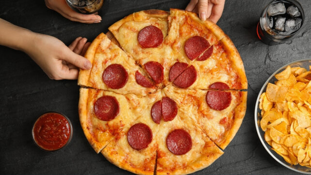 large salami pizza with slices being taken