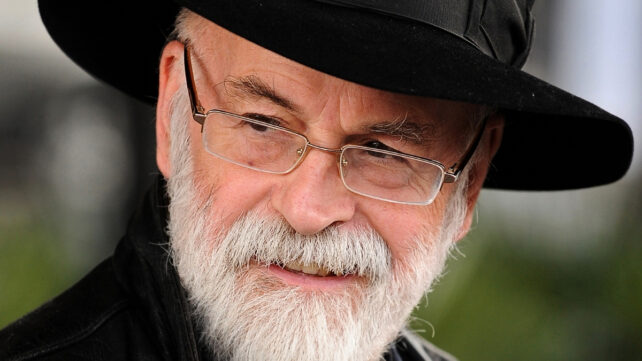 Terry Pratchett wearing a black top hat, gazing off to the left of the frame