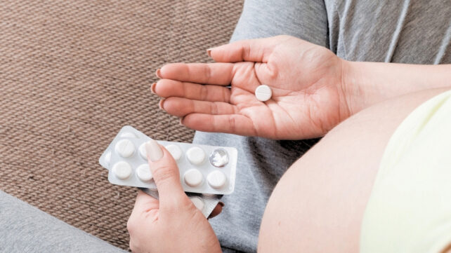pregnant woman holding pill in her hand