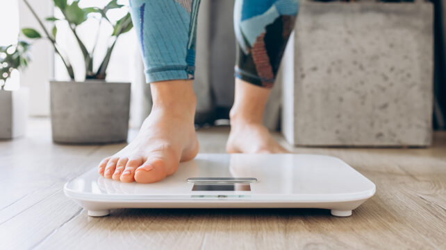 Close-up of bare feet stepping onto a digital scale